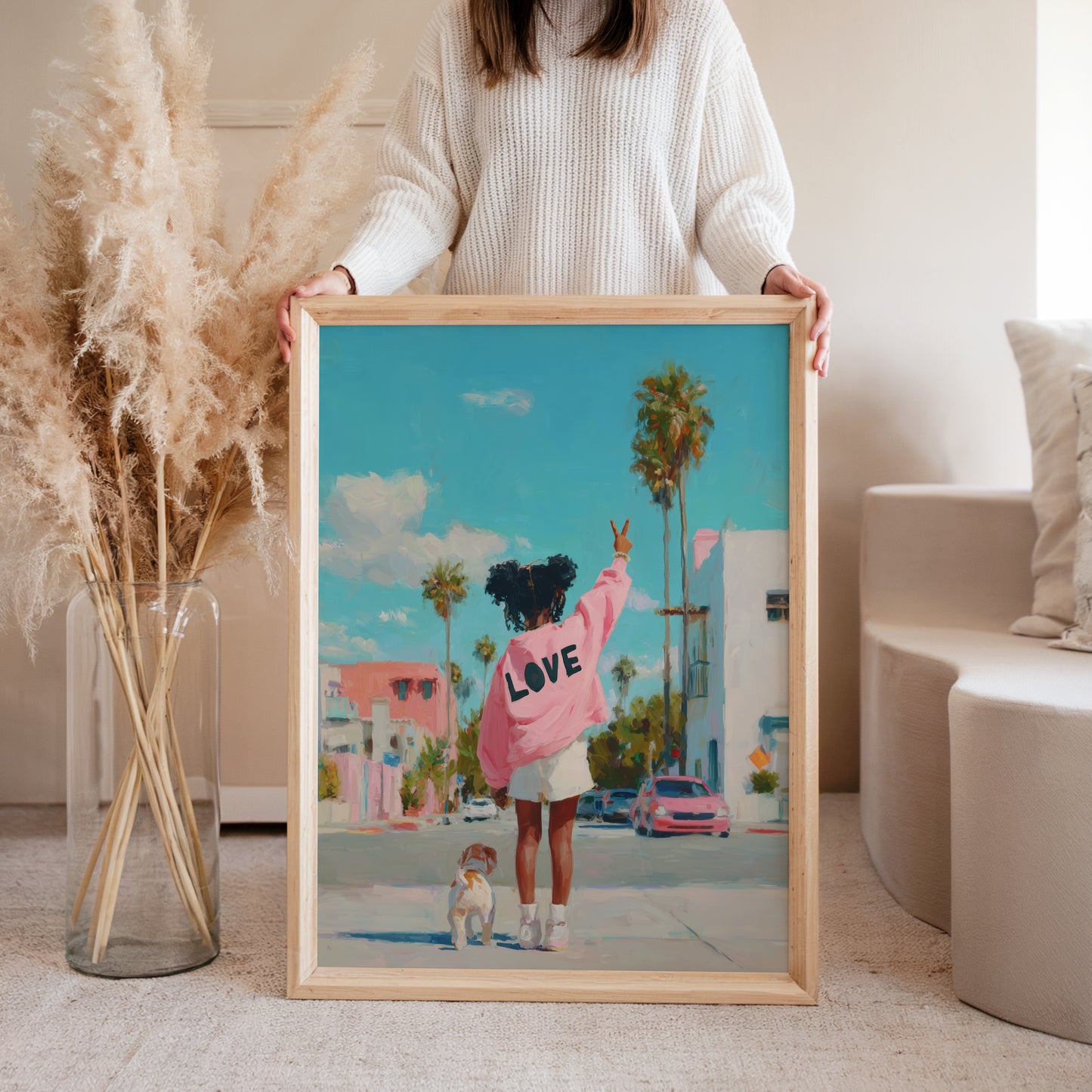 Woman holding framed Peace & Dog retro art print featuring a girl in pink LOVE jacket with a dog, colorful street scene wall art by Casa Loulou